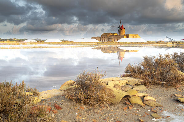 Reflection of the old windmill at the salt flats, saline dello Stagnone, Marsala, Trapani province, Sicily, Italy