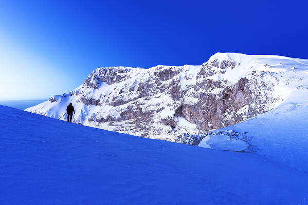 Man takes photographes at dusk in front of the Cantari snow covered mountain peak, Apennines, Simbruini regional park, Frosinone province, Latium, Italy