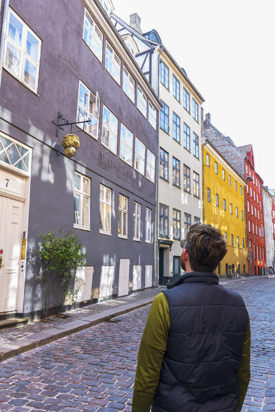 Man admiring the facades of colourful buildings in the cobbled medieval Magstraede street, Copenhagen, Hovedstaden Denmark, Europe
