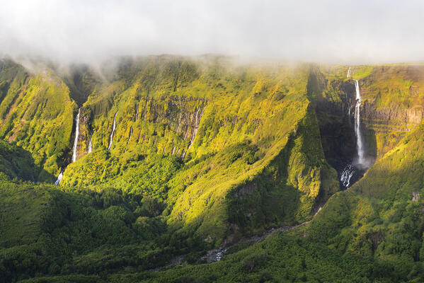 Elevated view of the Ribeira do Ferreiro and Ribeira Grande waterfalls with clouds at sunset, Poco Ribeira do Ferreiro (Alagoinha), Lajes das Flores municipality, Flores Island (Ilha das Flores), Azores archipelago, Portugal, Europe
