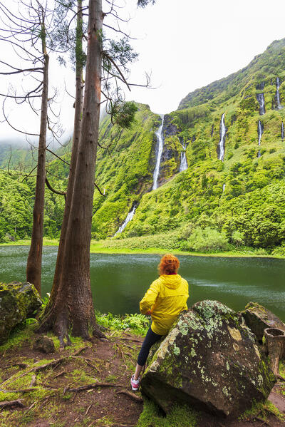 Woman sits and admires the waterfall of Ribeira do Ferreiro, Poco Ribeira do Ferreiro (Alagoinha), Lajes das Flores municipality, Flores Island (Ilha das Flores), Azores archipelago, Portugal, Europe