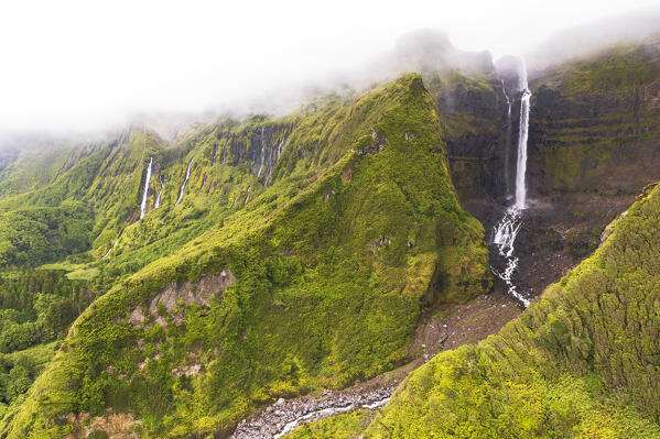 Aerial view of the Ribeira do Ferreiro and Ribeira Grande waterfalls with clouds, Poco Ribeira do Ferreiro (Alagoinha), Lajes das Flores municipality, Flores Island (Ilha das Flores), Azores archipelago, Portugal