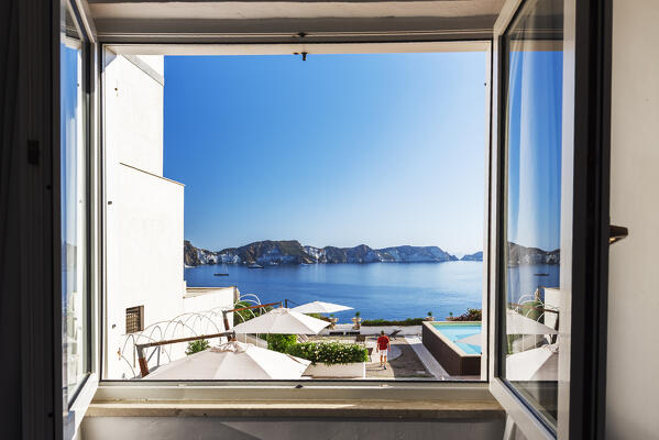View throught an open window of the mediterranean cliffs of the island of Ponza with a man overlooking the bay, Ponza island, Archipelago Pontino, Latina province, Latium, Italy