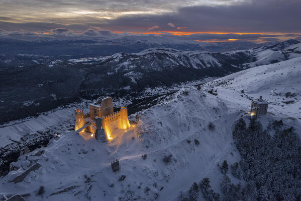 Illuminated drone view of the castle of Rocca Calascio and the church  Santa Maria della Pietà at dusk, Gran Sasso e Monti della Laga National Park, Apennines, L'Aquila province, Abruzzo region, central Italy, Italy, Europe