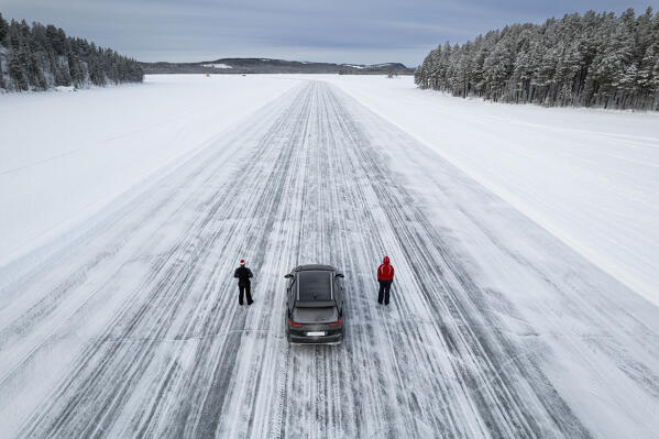 Drone view of a couple of people standing beside their car on a icy road of a frozen lake, Jokkmokk, Swedish Lapland, Norrbotten, Sweden, Scandinavia, Europe