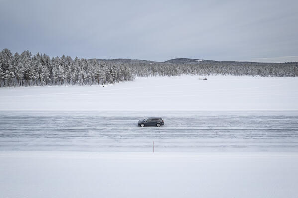 Aerial side view of a car travelling the empty icy road of a frozen lake, Jokkmokk, Norrbotten, Swedish Lapland, Sweden, Scandinavia, Europe