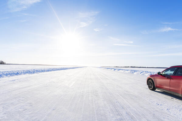 Red car travelling the frozen road on the icy sea, winter view, Lulea archipelago, Norrbotten, Swedish Lapland, Sweden, Scandinavia, Europe