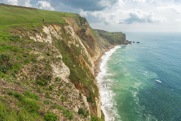 View of a hiker standing on top of the cliff of Lulworth Cove, Jurassic Coast, UNESCO World Heritage Site, Dorset, England, United Kingdom