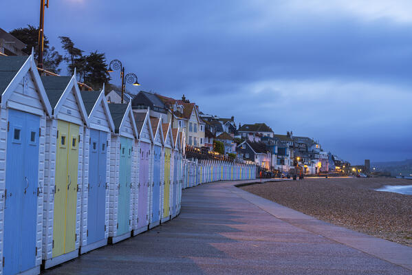 Multi-coloured beach huts on the beach of Lyme Regis at dusk, Jurassic Coast, UNESCO World Heritage Site, Dorset, England, United Kingdom