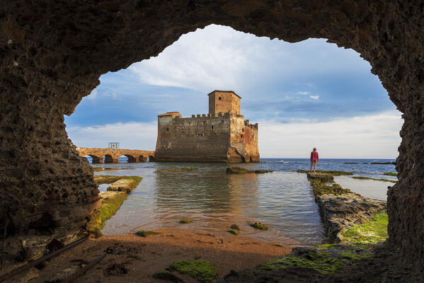 Tourist standing in front of the medieval castle of Torre Astura at sunset, Nettuno municipality, Rome province, Latium, Tyrrhenian sea, Italy, Europe