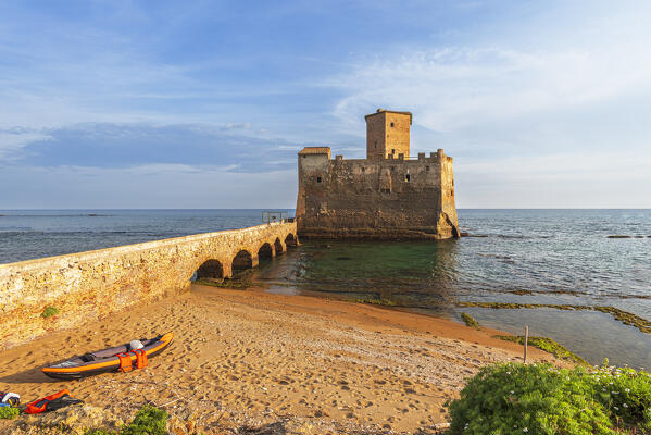 The golden beach in front of the medieval castle of Torre Astura with a kayak in the foreground, sunset view, Nettuno municipality, Rome province, Latium, Tyrrhenian sea, Italy, Europe