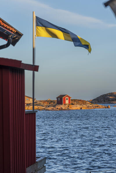 Small red wooden cottage on isolated granite island off the coast of Bohuslan lit by sunrise, Vastra Gotaland county, Swede, Scandinavia, Europe