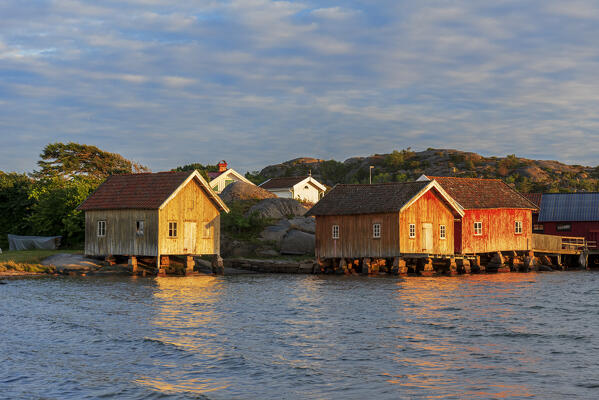Colored and old fishing houses lit by sunset, Bohuslan, Sweden, Scandinavia, Europe