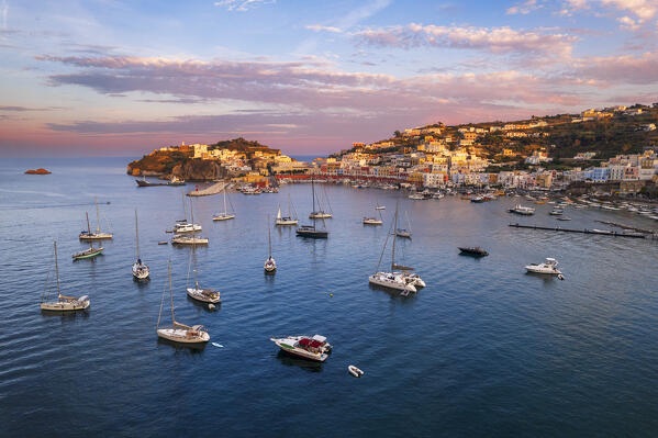 Sunset above the colorful fishing village of Ponza with boats anchored in the bay, aerial view, Ponza island, Pontine islands, Tyrrhenian Sea, Latina province, Latium, Italy, Europe