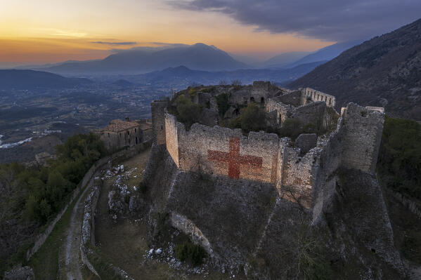 Sunset on Vicalvi medieval castle with the typical red cross painted on the perimetral wall on top of a hill surrounding the countryside, aerial view, Vicalvi, Frosinone province, Ciociaria region, Latium, Italy, Europe