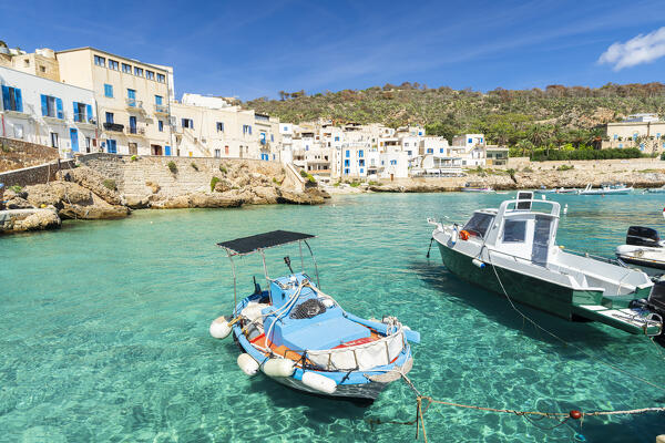 Traditional sicilian wooden boat floats in the crystal water of the island of Levanzo with the typical white-washed houses in the background, Favignana municipality, Trapani, Aegadian islands, Mediterranean Sea, Sicily, Italy