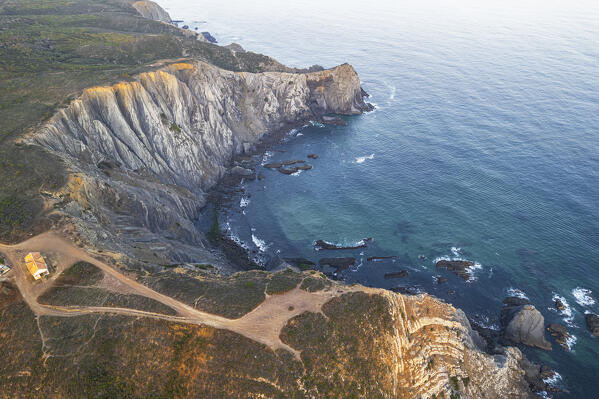 Dramatic aerial view of rocky cliff surronding a tiny bay at sunrise, Sagres, Algarve, Atlantic Ocean, Portugal, Europe