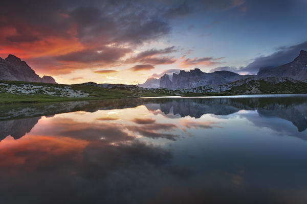 Dolomites, Italy. Clouds and colors at dawn are reflected at Laghi dei Piani, not far from Locatelli hut in Sesto Dolomites.
