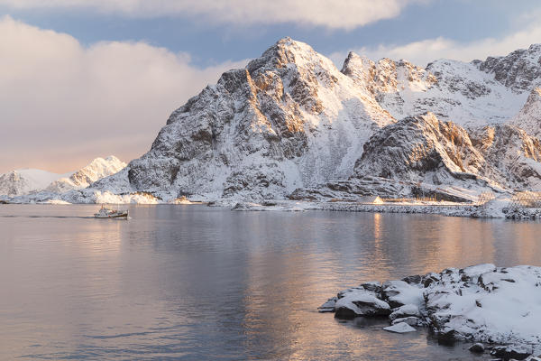 Snowy mountains edging the icy waters of Henningsvær Fishing village, Lofoten Islands, Norway