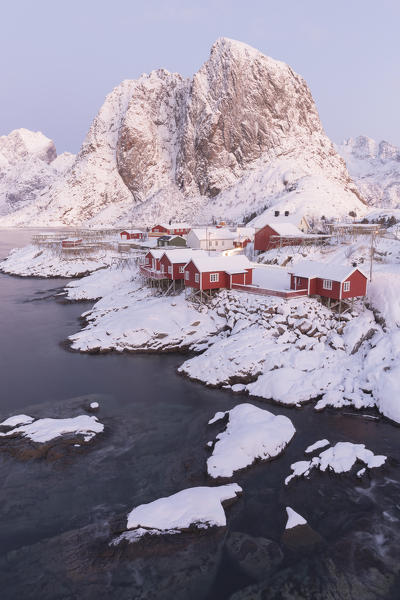 The snowy peaks and frozen sea frame the typical fisherman houses called Rorbu, Hamnøy, Lofoten Islands, Northern Norway, Europe