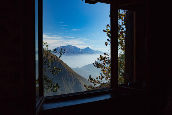 View on the Grigne mountains group through the window of a hut in val Cavargna, Carlazzo, Province of Como, Lombardy, Italy, Europe