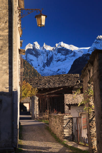 Typical path of the alpine village of Soglio at sunset, with Sciora mountains in the background, Soglio, Val Bregaglia, Grisons, Switzerland, Europe