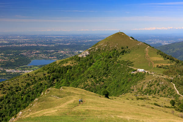 Hikers on the grass of the ridge of Monte Rai in front of Monte Cornizzolo, Triangolo Lariano, Brianza, Province of Lecco, Lombardy, Italy