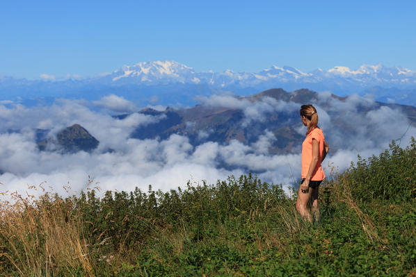 Hiker on the path leading to the summit of Monte San Primo looking at Monte Rosa, Triangolo Lariano, Bellagio, Province of Como, Lombardy, Italy
