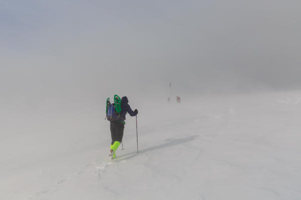 Hiker reaching the summit of monte Bar mountain surrounded by a wind storm, val colla, canton ticino, switzerland, europe