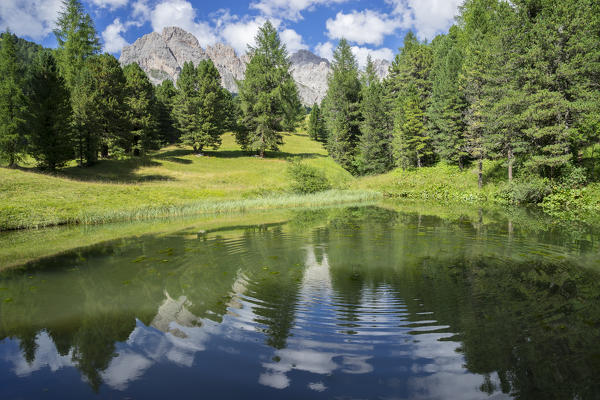 Odles mountain range reflected in a small lake in Summer, Dolomites, Italy