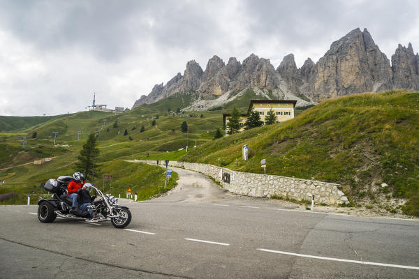 Biker on Gardena pass, Cir range on the back, Odle, Dolomites, Sudtirol, Italy