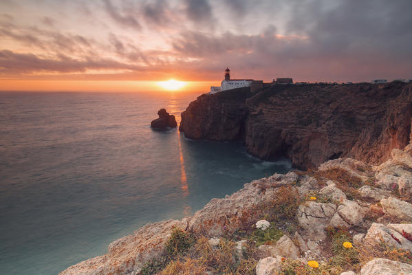 Sunset frames the lighthouse overlooking the Atlantic Ocean Cabo De Sao Vicente Sagres Algarve Portugal Europe