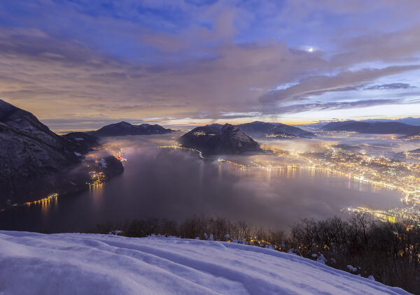 dusk over Lugano city and Lake Lugano at dawn after snowfall seen from the top of monte Bre, Canton of Ticino, Switzerland, Europe