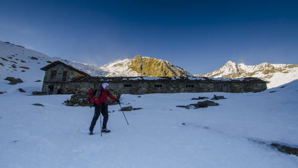 Alpinist in front of a pasture (Soana valley, Gran Paradiso National Park, Piedmont, Italian alps, Italy)