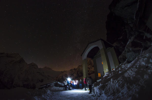 Faithful sitting in front of the sanctuary of San Besso at night (Val Soana, Gran Paradiso National Park)