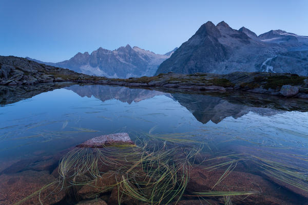 Genova valley, Carisolo, Adamello Brenta natural park, Trentino Alto Adige, Italy. The three Lobbie are reflected in one of the many lakes that dot the plain where the shelter is located Mandron