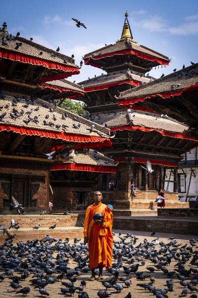 Nepalese Monk wearing orange robe holding urn for alms at Durbar Square Kathmandu, Nepal, Nepalese, Asia, Asian, Himalayan Country, Himalayas.