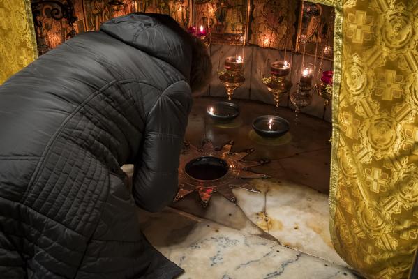 Pilgrim praying at the birthplace of Jesus Christ marked with a fourteen-point silver star, the Altar of the Nativity, Church of the Nativity, Bethlehem, Palestine, Middle East