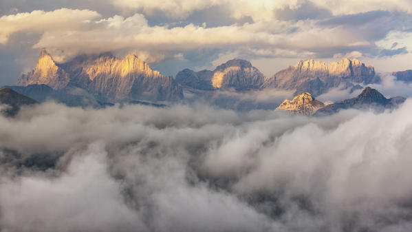 Europe, Italy, Veneto, Belluno. The sunset light on some dolomite's peak, surrounded by a sea of clouds, Dolomites