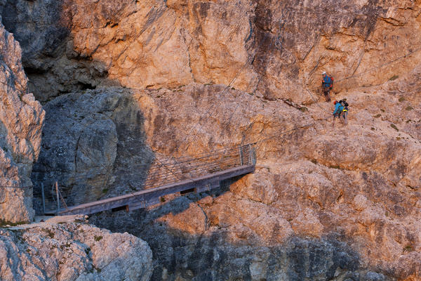 Europe, Italy, Veneto, Belluno. Two hikers near the suspended bridge with steel cables along the Kaiserjaeger trail, Lagazuoi, Dolomites