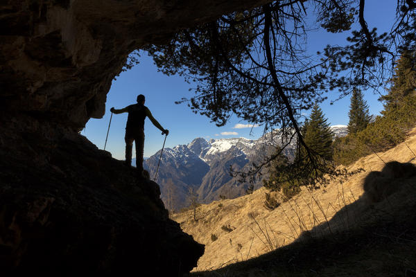Hikers in silhouette at the entrance of a small cave near the fork of the Canevuze, the southern area of the Monti del Sole, Belluno Dolomites National Park, horizontal