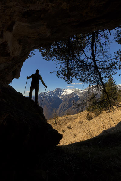 Hikers in silhouette at the entrance of a small cave near the fork of the Canevuze, the southern area of the Monti del Sole, Belluno Dolomites National Park, vertical