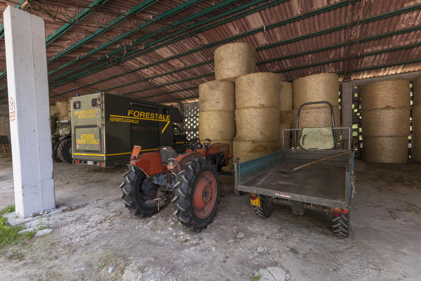 Tractors, equipment and bales of hay in the shed in front of the stables of Case Salet, State Natural Reserves, Monti del Sole