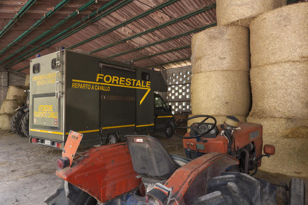 Tractors, equipment and bales of hay in the shed in front of the stables of Case Salet, State Natural Reserves, Monti del Sole