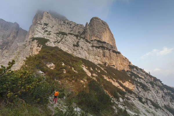 Europe, North Italy, Veneto, Belluno, Monti del Sole, Dolomites. Man looking at the first light on the north face of Piz de Mezodi.