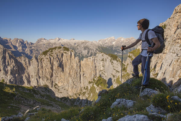 Hikers at Passo del Ciodo admire the panorama to the steep walls of the Third and Fourth Pala. In the background the plateau of the Pale di San Martino. Dolomites, Pale di San Lucano, Agordino, Belluno, Veneto, Italy