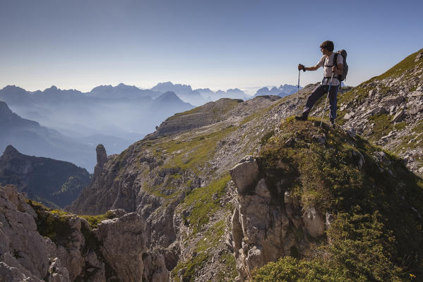 Hikers near Passo del Ciodo looking at the landscape, in the bottom the curious bell tower of Besausega. Pale di San Lucano, Dolomites, Agordino, Belluno, Veneto, Italy, Europe