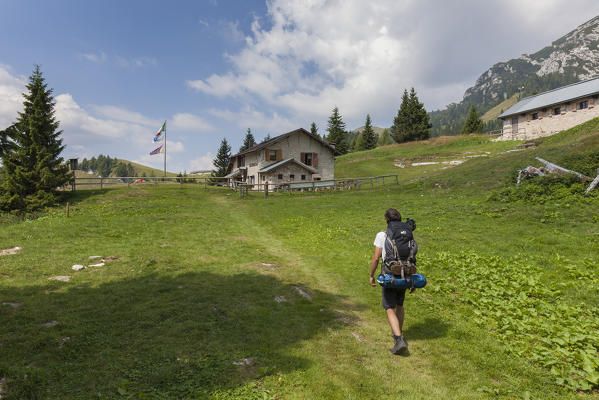 Europe, Italy, Veneto, Belluno. Hikers get to the Boz alpine hut, on the lawns of the Neva in the Cimonega group, Cesiomaggiore, Dolomites, Belluno Dolomiti National Park