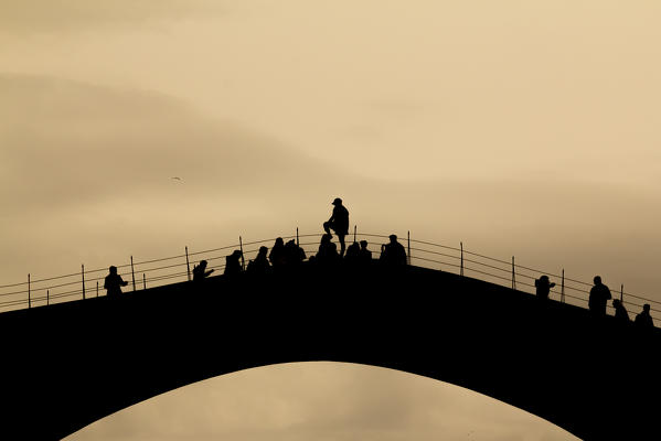 Eastern Europe, Bosnia and Herzegovina. 
Tourists on the Stari Most (the Old Bridge) awaiting the famous jump in the Naretva river