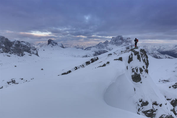 Europe, Italy, Veneto, Belluno. Hiker admires the sunset over the snow capped ridges, Mondeval, Dolomites